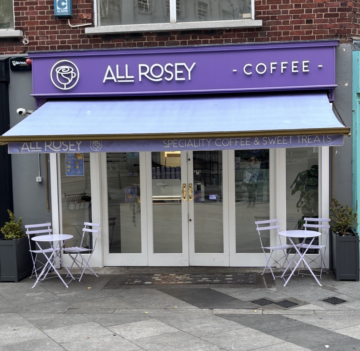 The All Rosey shopfront on South King Street: a purple fascia, a lilac awning and bistro tables on the pavement.