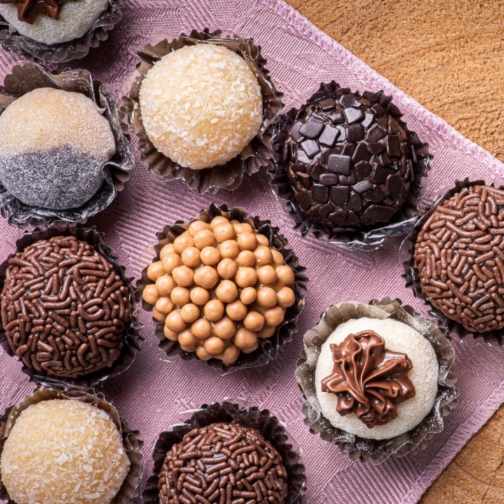 A tray of brigadeiros in coconut, chocolate sprinkles, caramel pearls and dark chocolate.